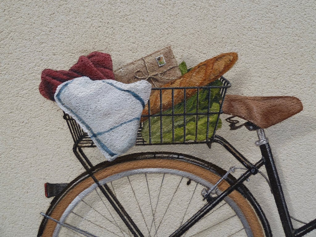 Détails d'un panier de vélo peint dans une fresque en trompe-l'oeil. Une baguette, une enveloppe.
