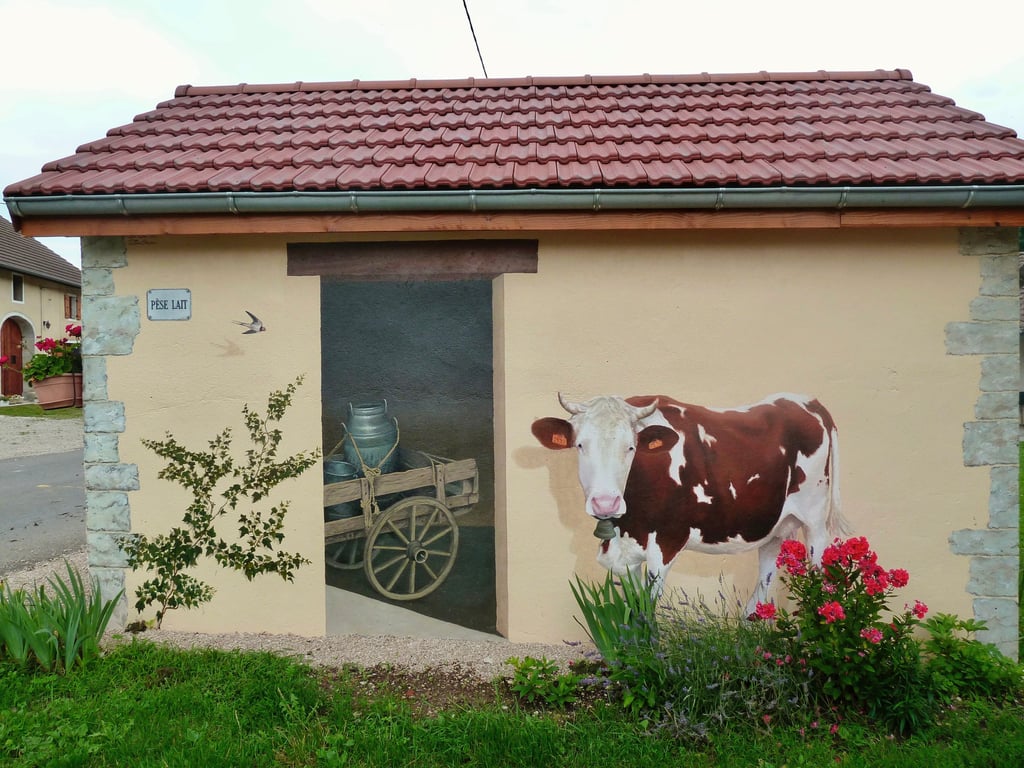 Fresque murale réalisée sur une façade, fausse porte, vache, lierre, pierres: tout est peint !...