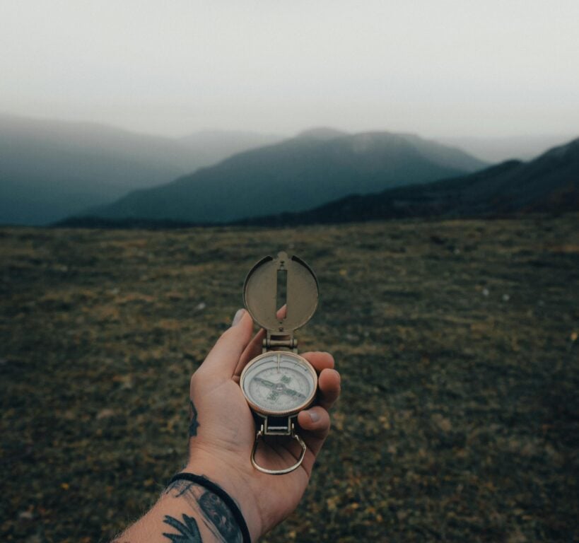 Holding compass over mountain trail, navigation and orienteering in wilderness