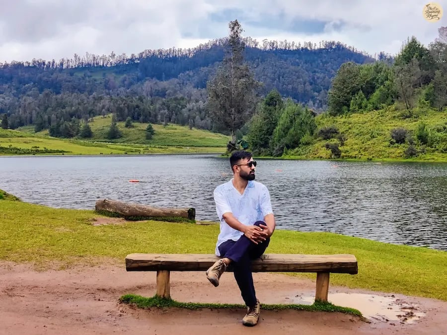 Traveler resting on a bench at the shore of Mannavanur Lake, heart-shaped beauty in Kodaikanal.