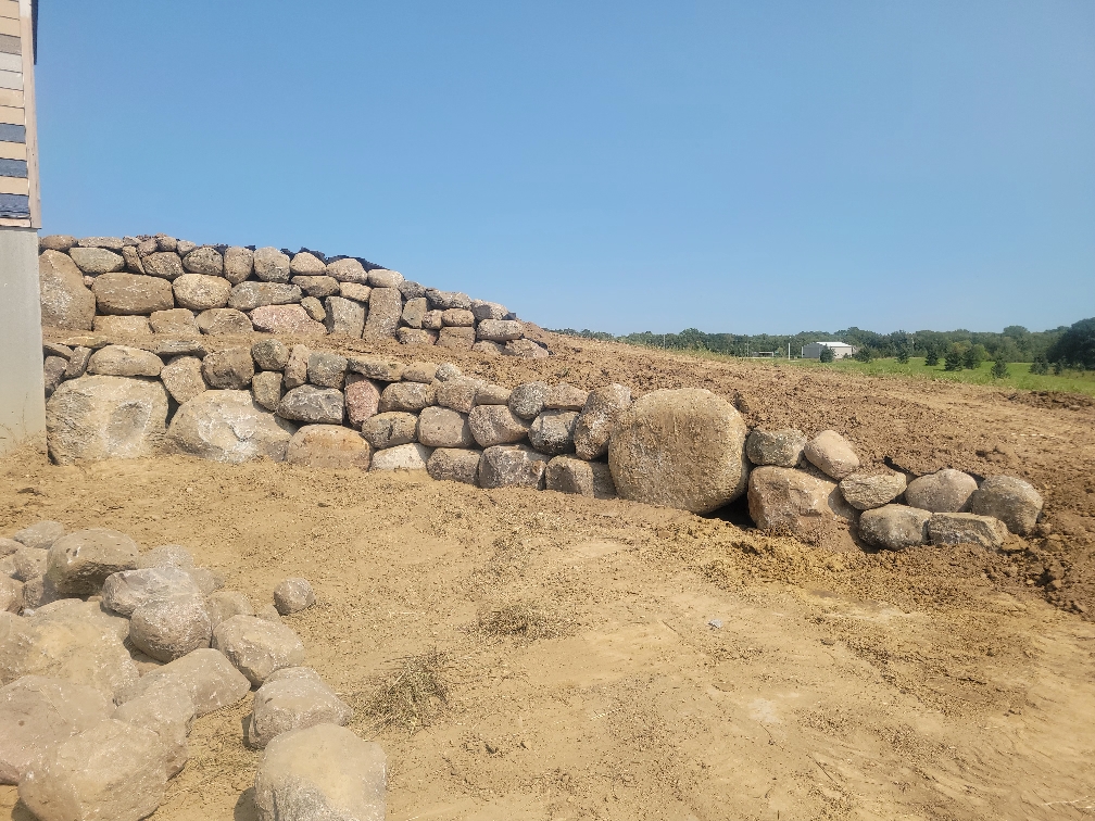 Large boulder retaining wall construction in Central MN.