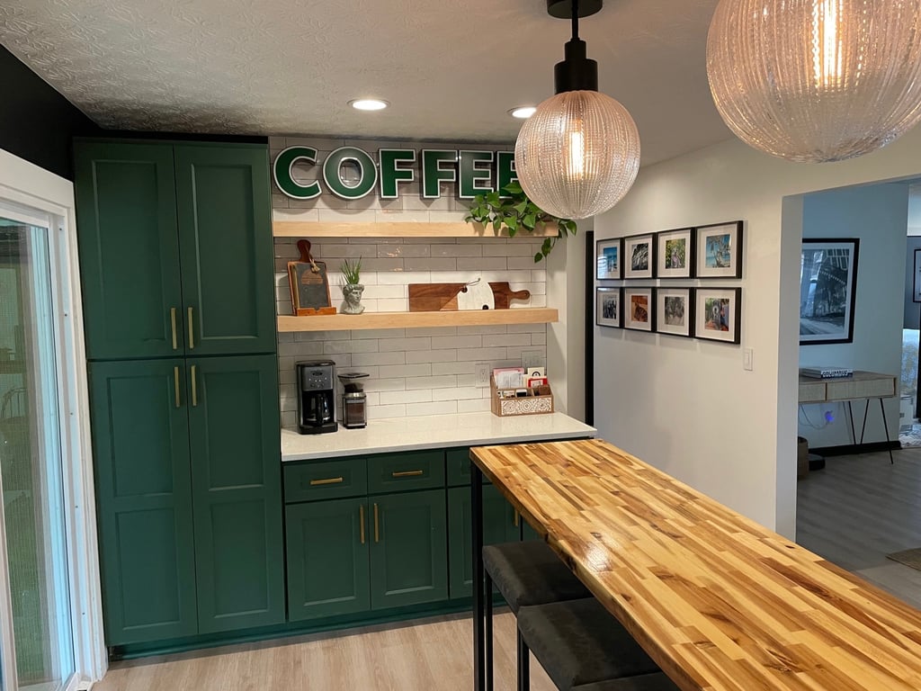 Modern home coffee station with green cabinets, butcher block table, and globe pendant lighting.