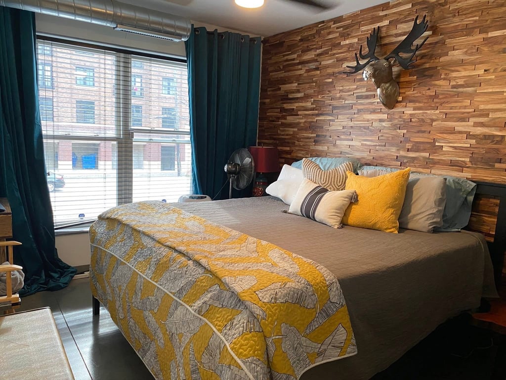 Modern bedroom with wood accent wall, moose head decor, and yellow patterned bedding.