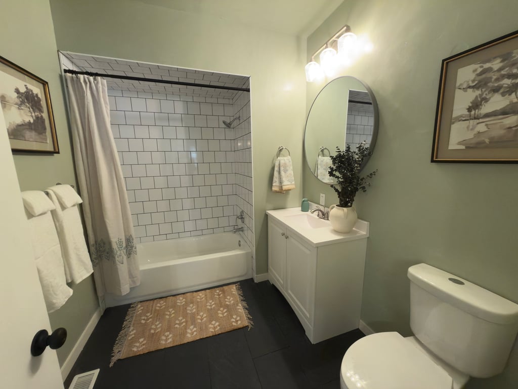staged Modern bathroom in Ohio with sage green walls, subway tile bathtub.