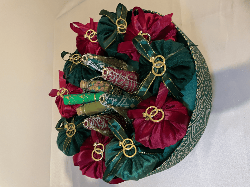 Green and burgundy velvet pouches with gold rings in a henna night favor basket.