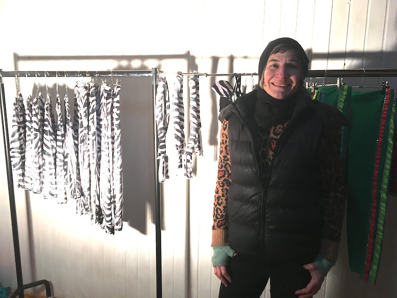 samuko standing next to a clothing rack of zebra print costumes..