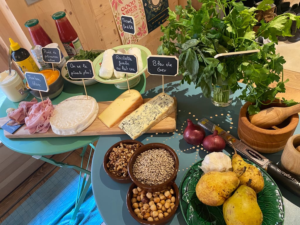 Gourmet cheese board with blue cheese, ham, nuts, and fresh herbs on a rustic table.