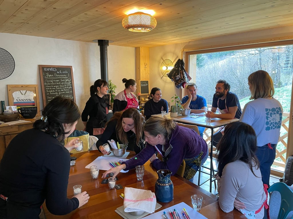 A group of people participate in a creative workshop at a wooden table in a rustic lodge.