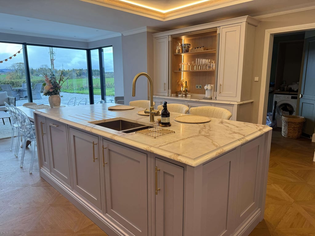 Luxury kitchen island with white marble countertop, gold faucet, and elegant grey cabinetry.