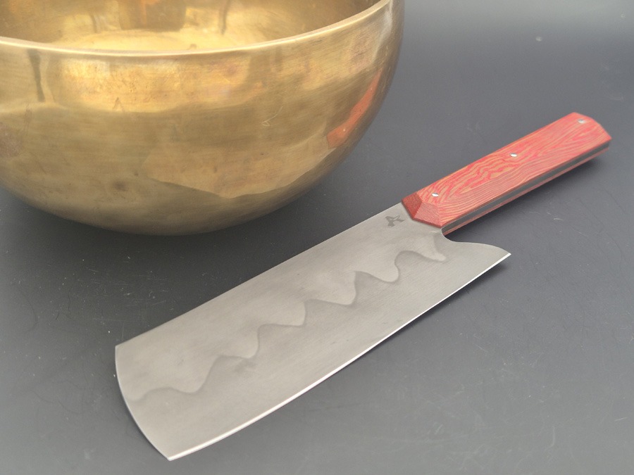 Couteau de cuisine polyvalent avec manche rouge à coté d'un bol dorée