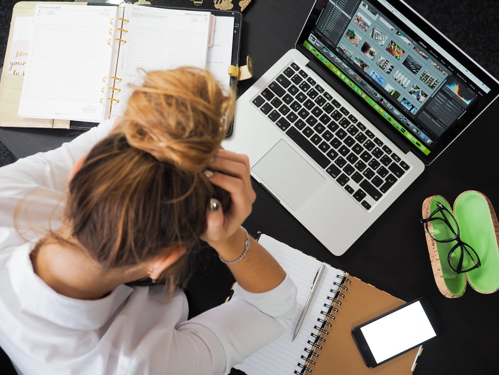 a woman sitting at a desk with a laptop and a notebook - She needs the No BS Revenue Reset