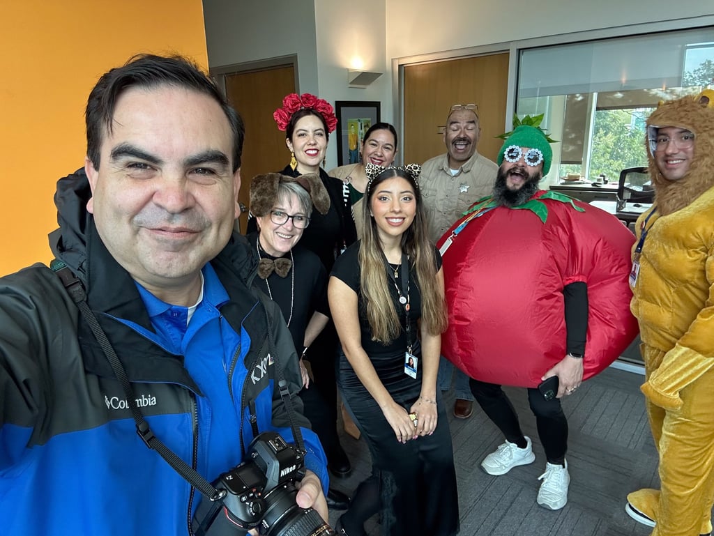 Francisco holds a camera, smiling with Southwest Key’s creative team in festive, fun costumes.