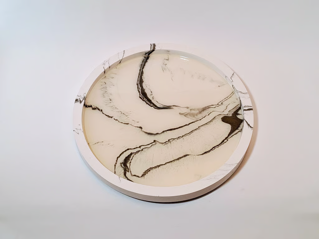 Handmade round marble effect resin tray with black and white swirls for modern home decor.