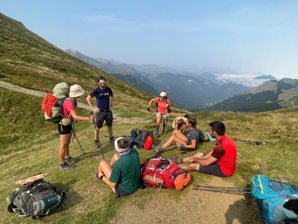 Un groupe de randonneurs, sacs à dos et bâtons de marche à la main, se repose sur une crête