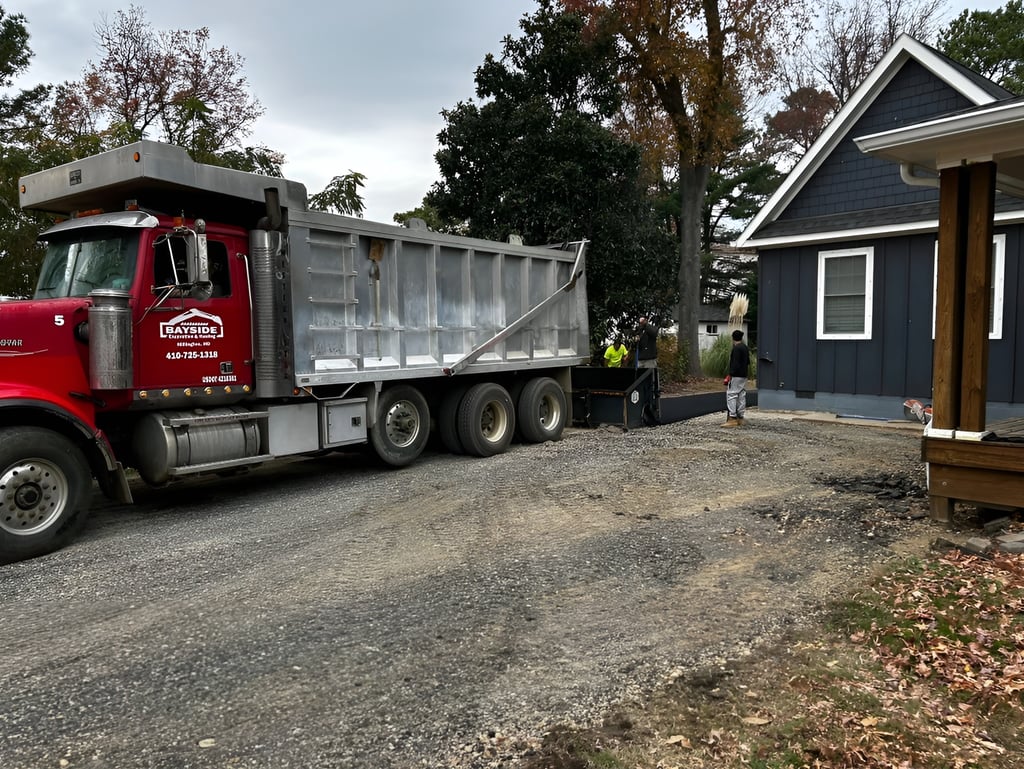 Red dump truck unloading gravel on a residential driveway for a professional paving project.