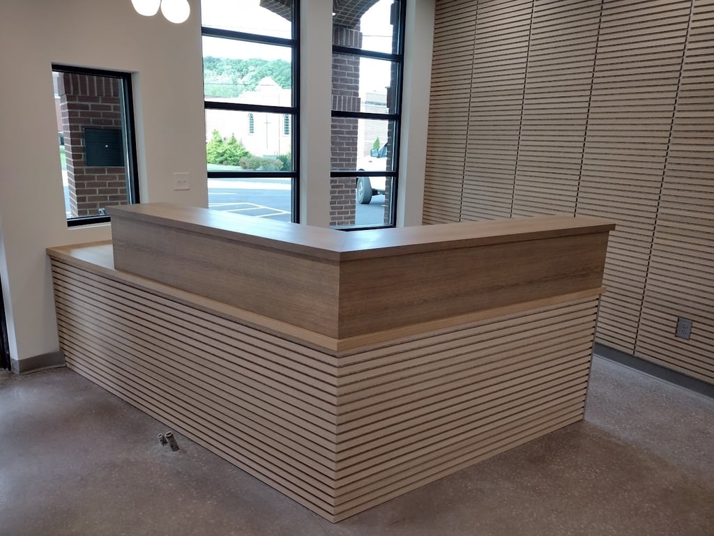 Custom wood reception desk with slat wall paneling in a modern office lobby.