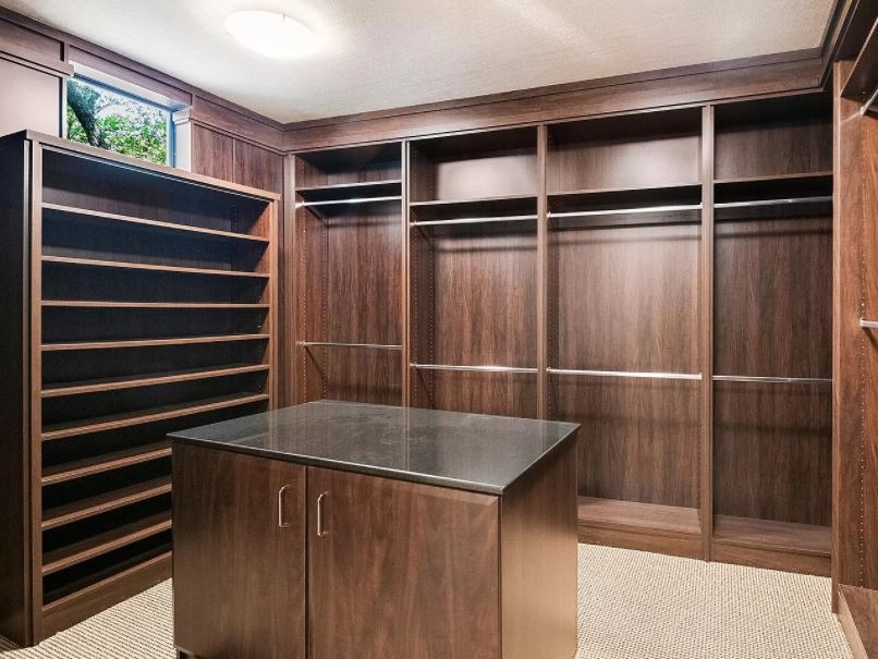 Spanish Trails walk-in closet w/dark wood custom cabinetry w/center island granite countertop.