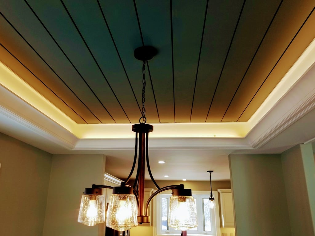Elegant bronze chandelier with seeded glass shades hanging from a coffered shiplap ceiling with cove lighting.