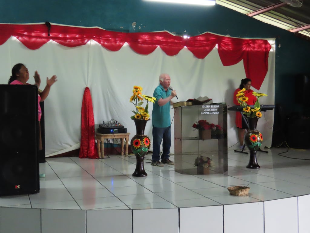 Pastor Esmerito Reyes stands behind a podium preaching to a congregation.