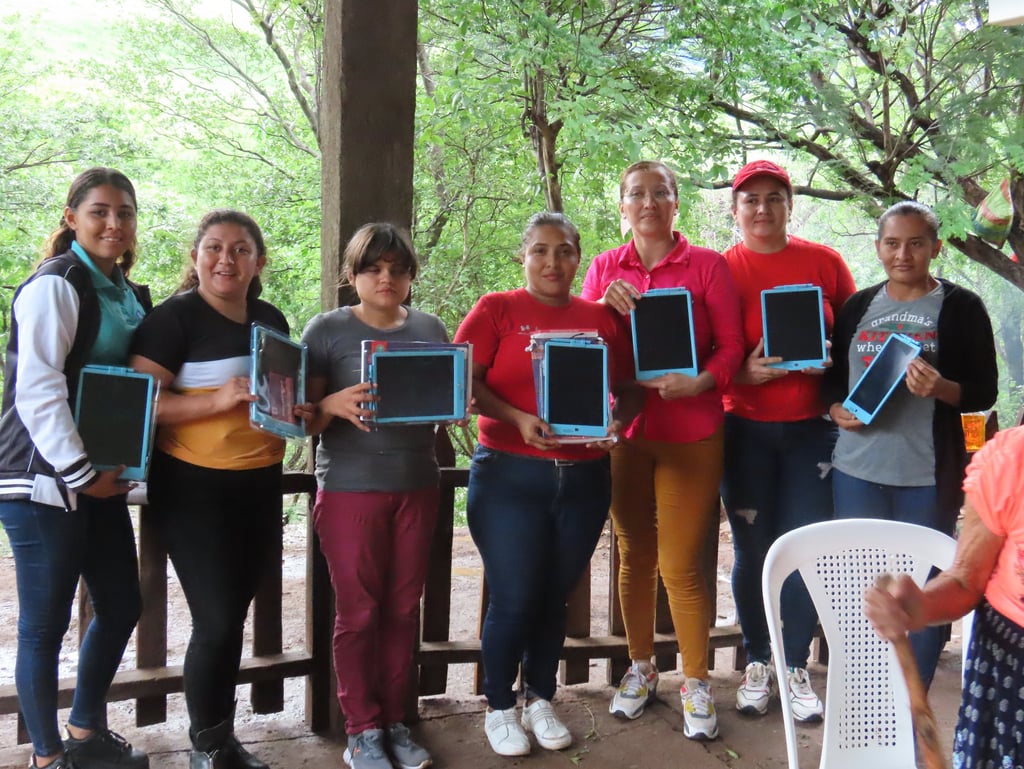 Teachers stand together in a line, presented with tablets.