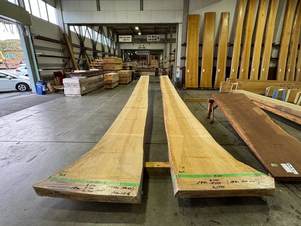 Two long, raw natural wood slabs displayed in a Japanese lumber warehouse for woodworking.