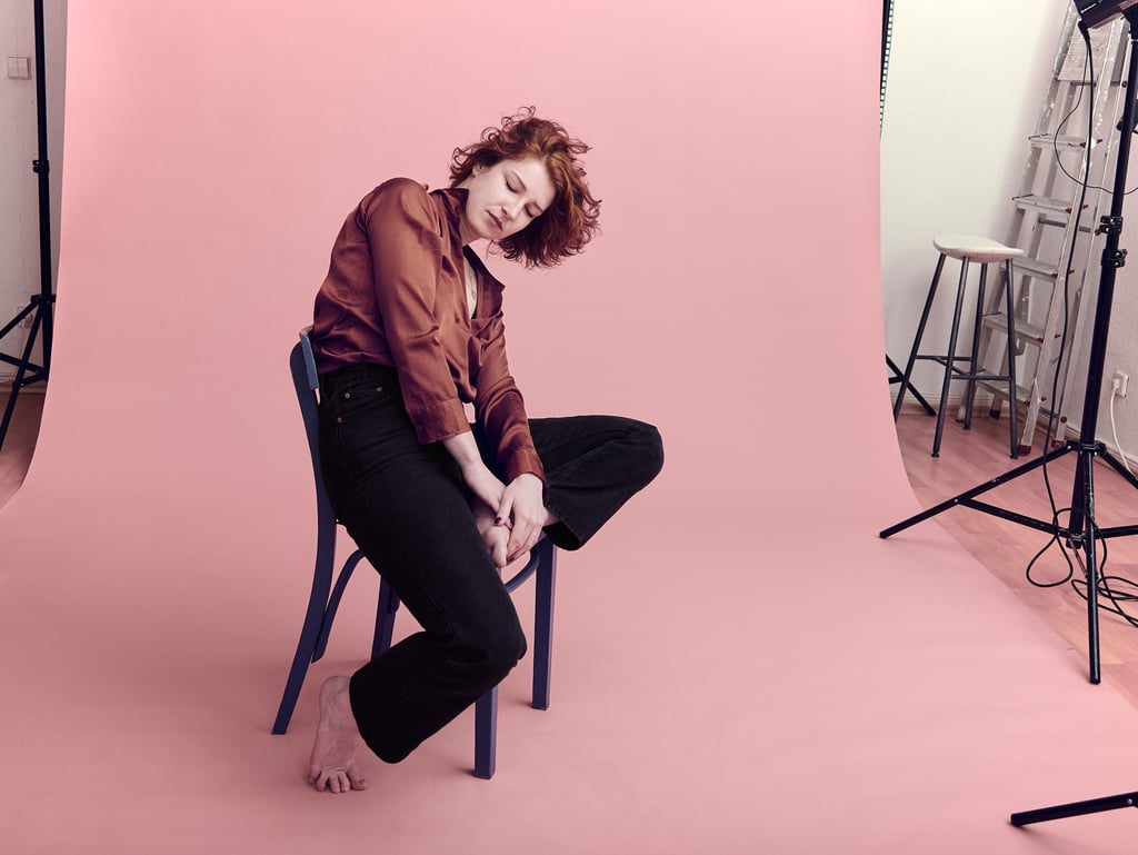 Young woman sitting on a blue chair is a photography studio.