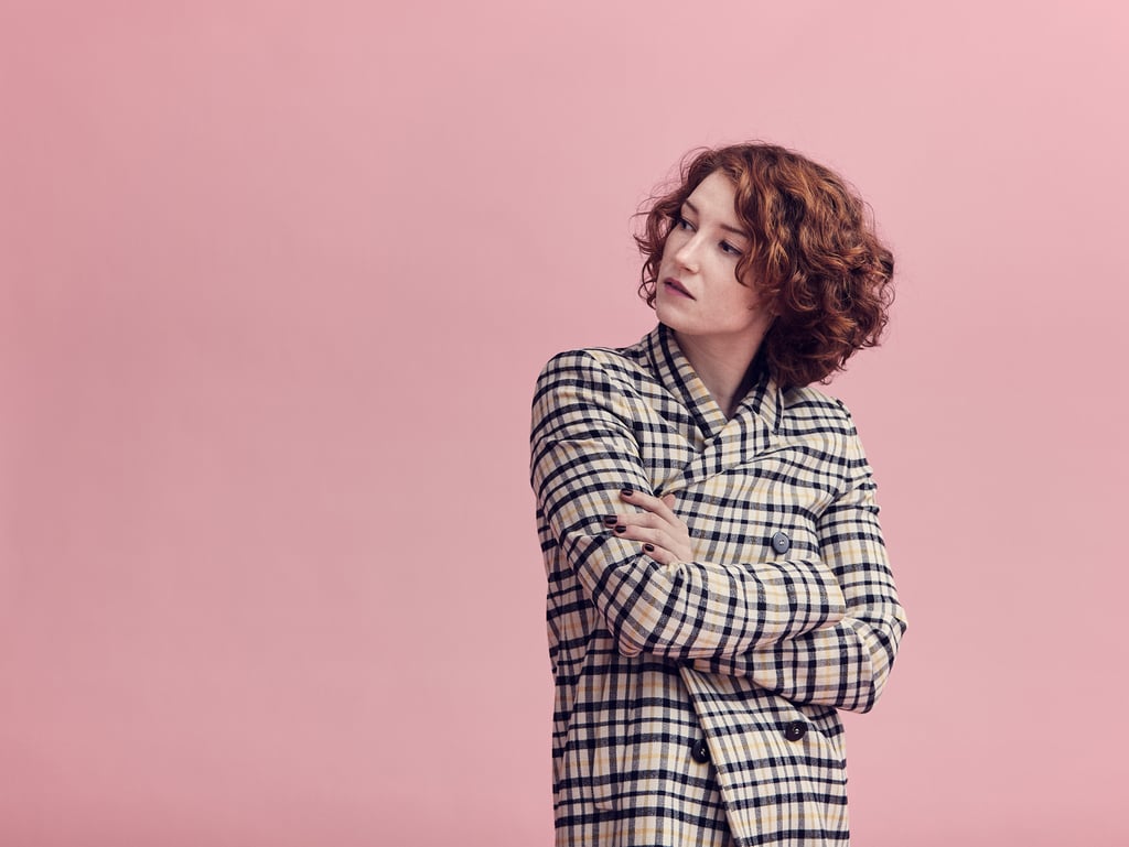 A woman with curly red hair wearing a coat.