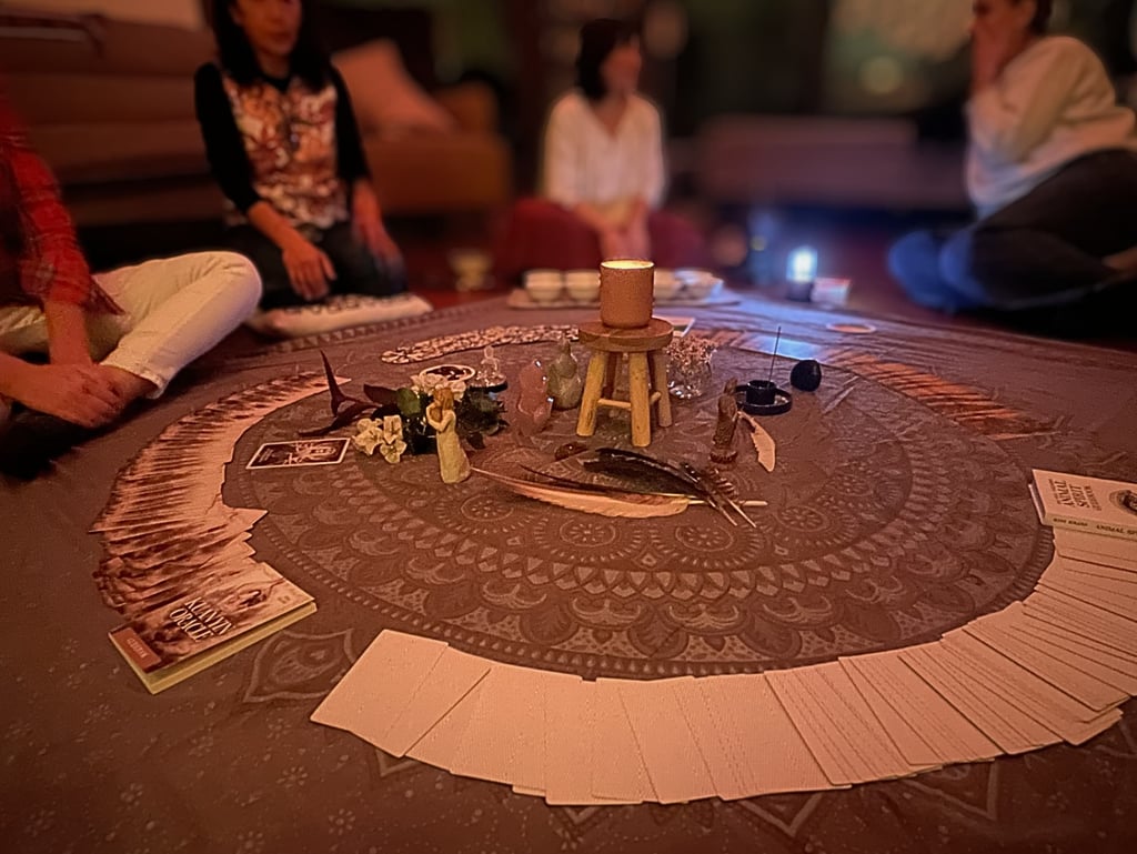 women sitting in circle around oracle cards and artefacts