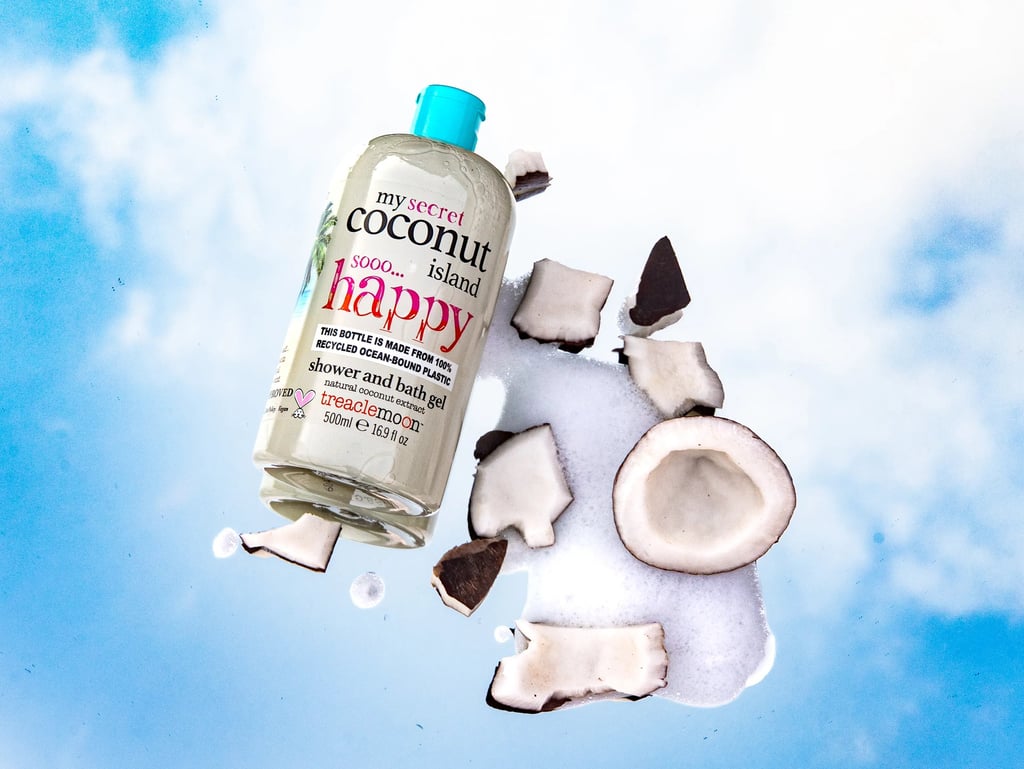 Treaclemoon Coconut Island shower gel surrounded by coconut pieces and foam on a cloudy blue sky