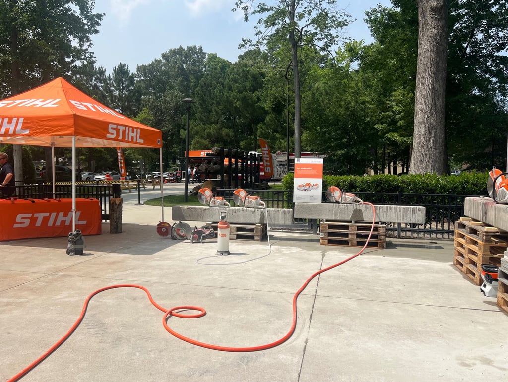 Stihl concrete saws and power equipment displayed at an outdoor demo event with orange tents.