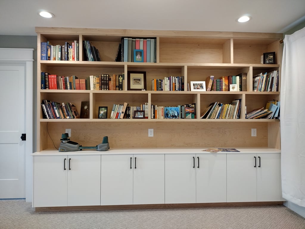 Custom built-in wooden bookshelves and white storage cabinets for home office organization.