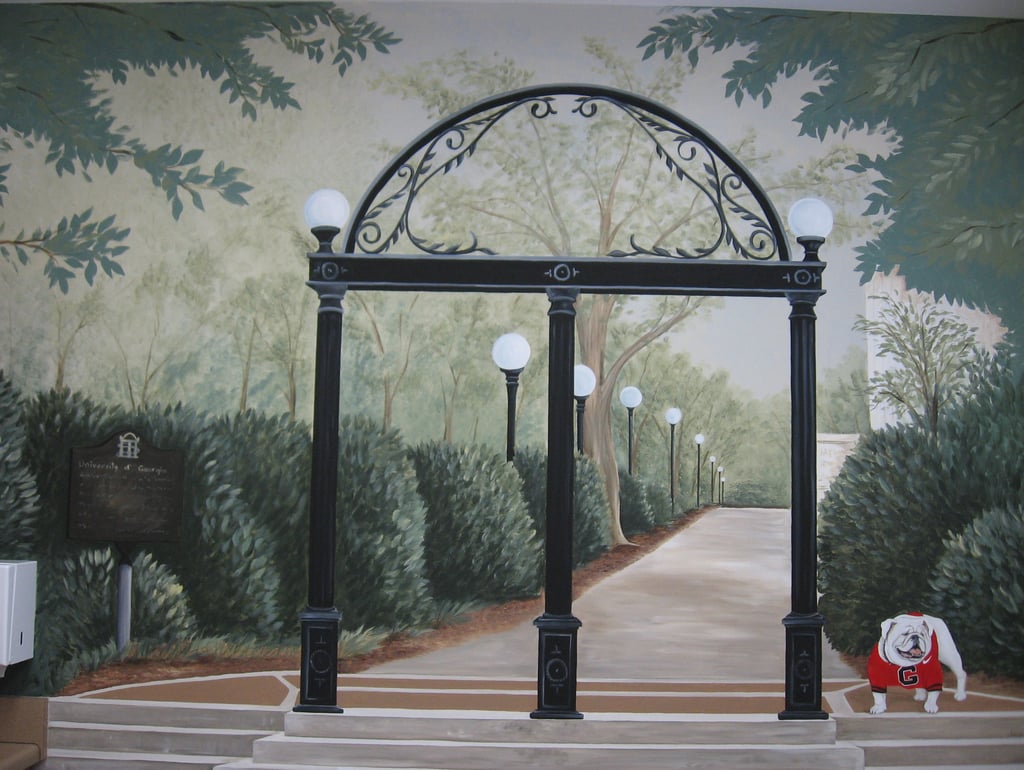 Mural of the University of Georgia Arch and Uga mascot bulldog on a campus walkway with lamp posts.