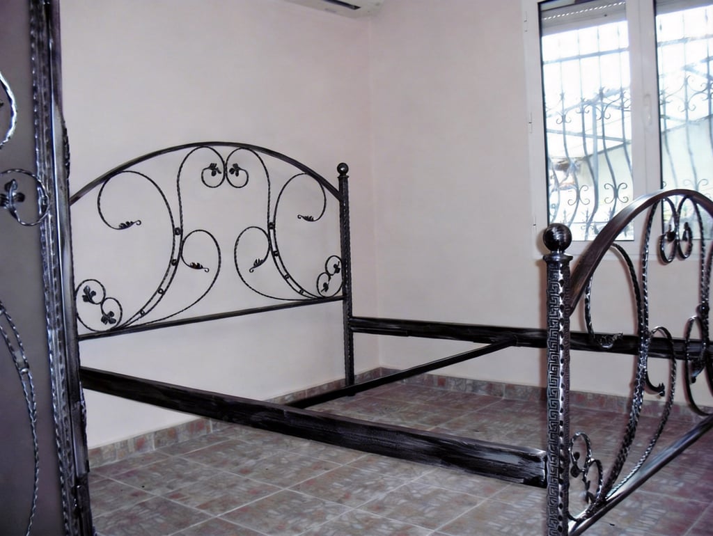 Elegant wrought iron bed frame with a decorative scrollwork headboard in a bedroom.