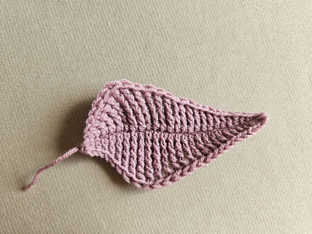 Handmade dusty rose crochet leaf applique featuring detailed stitch work on a neutral background.