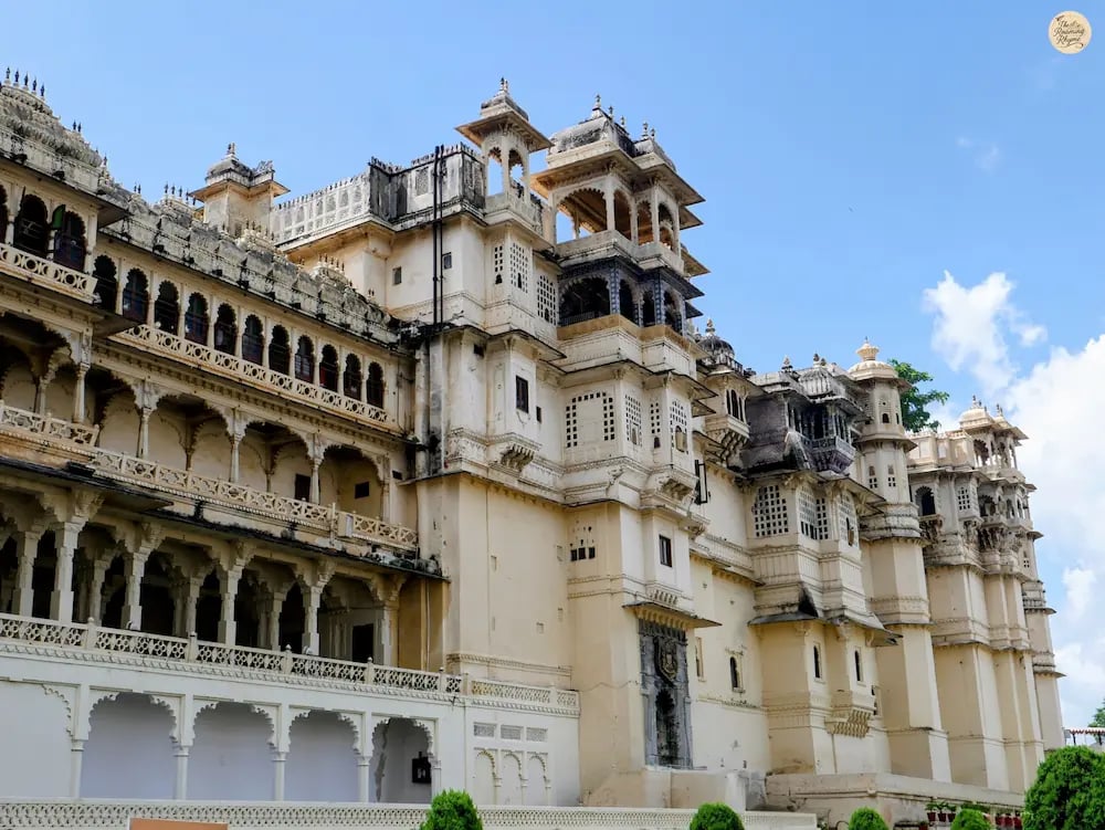 Facade of Udaipur City Palace viewed from Manek Chowk, showing domes, arches, and white marble walls.