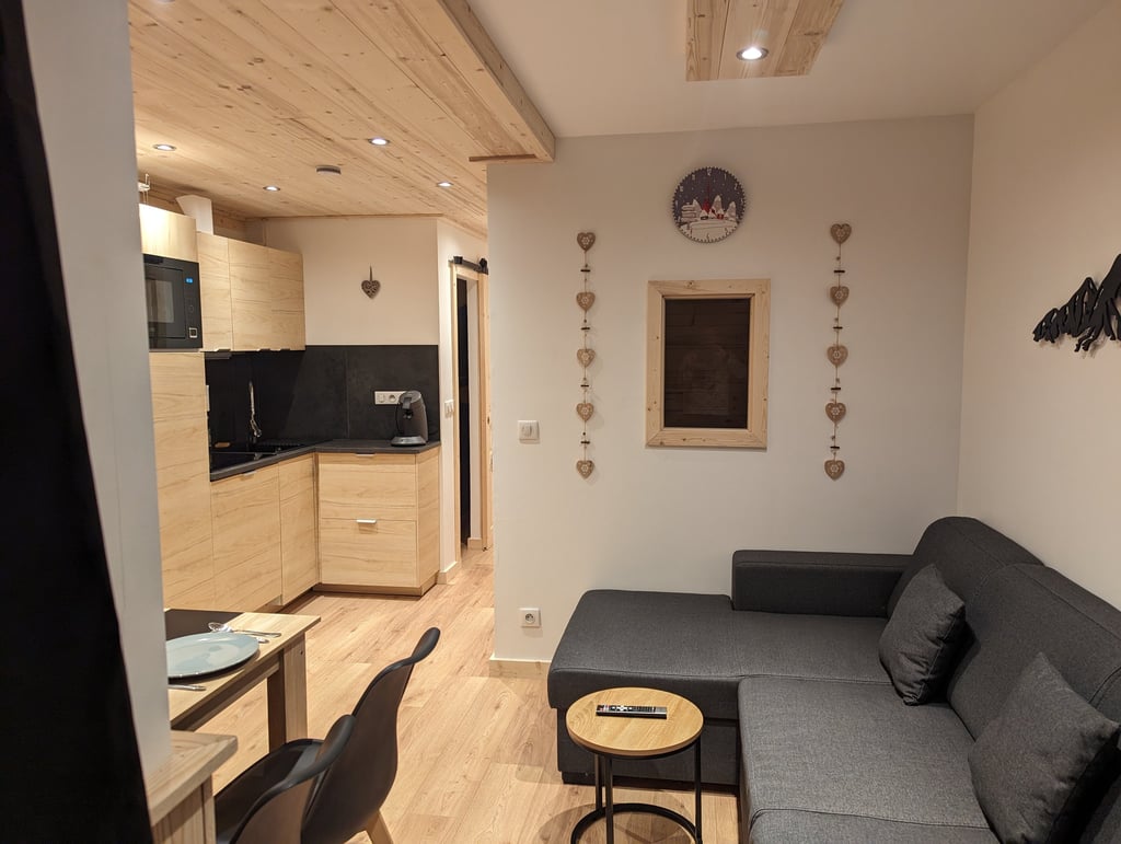 Open living space inside a warm Val Thorens ski apartment with lounge area, dining table and modern mountain kitchen