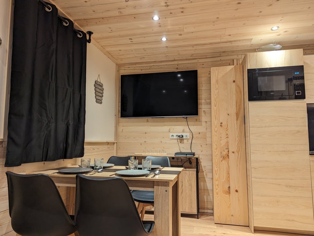 Dining and entertainment area inside a ski-in ski-out apartment with TV and warm wood interior