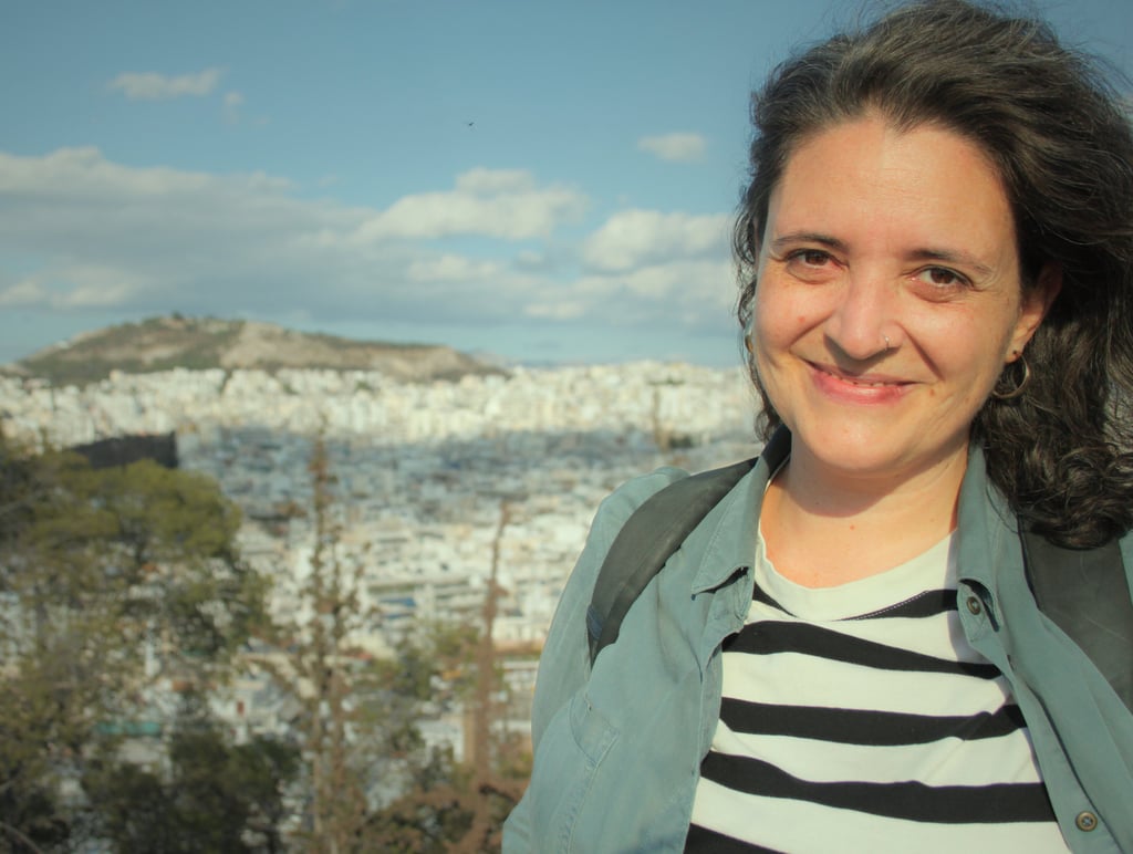 Ângela smiling with a city view behind her