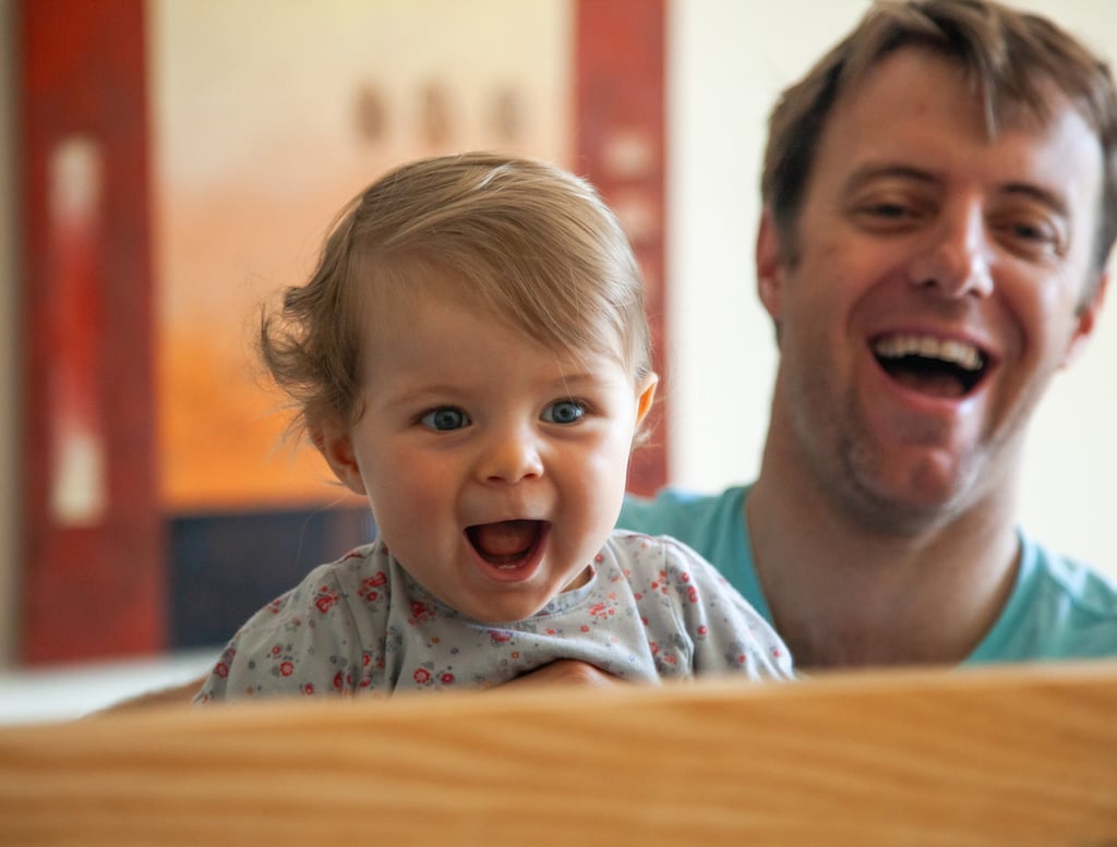a man and a baby are smiling and laughing in a mirror