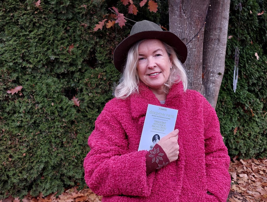 a woman in a pink jacket and hat holding a book