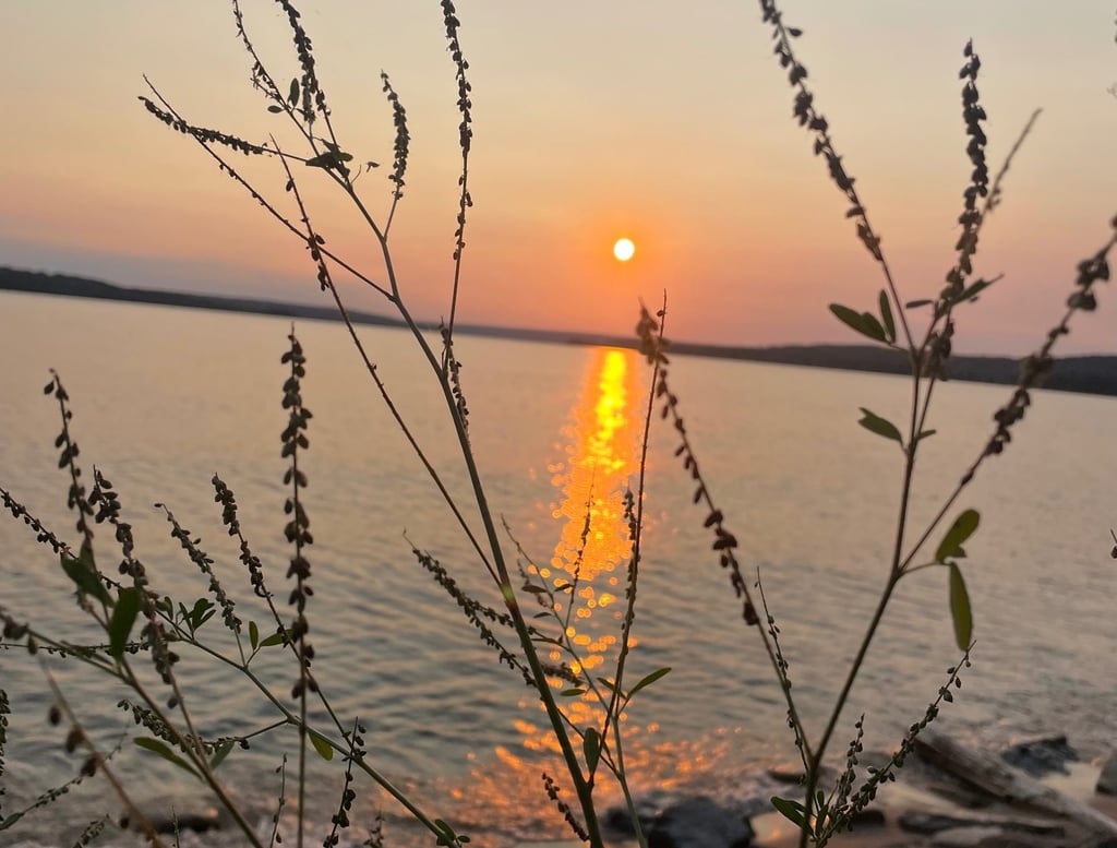a sunset over a lake with a sun setting