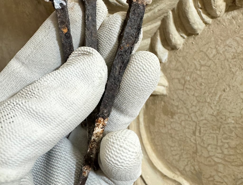 Roestige gesmede spijkers in het stucwerk.