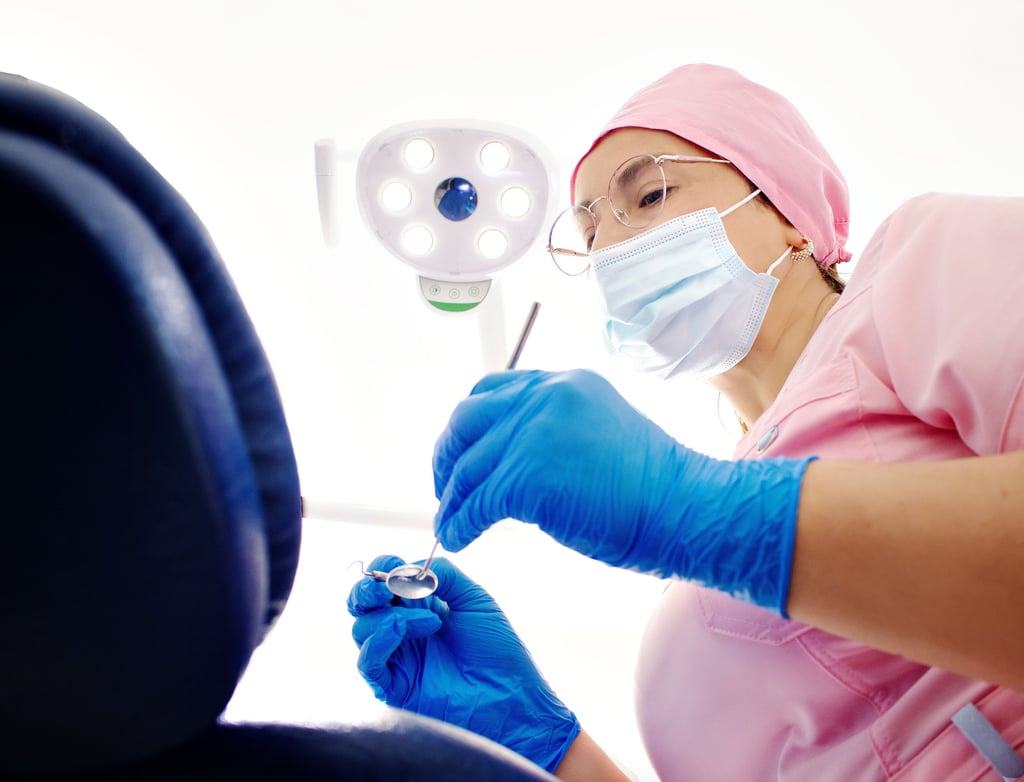 dentist woman in a pink shirt and blue gloves