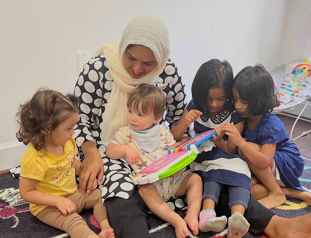 Caregiver and children reading an electronic book at daycare