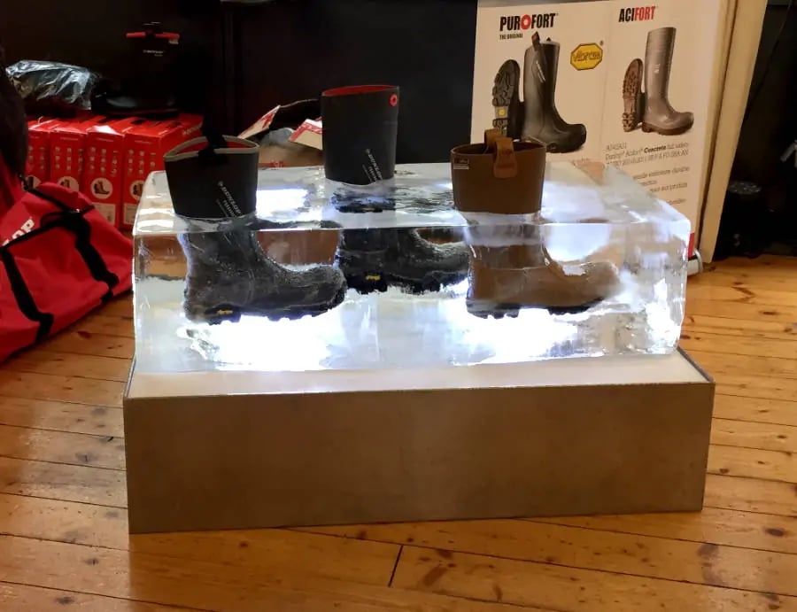 Insulated Dunlop Purofort waterproof work boots frozen inside a large block of ice for a thermal display.