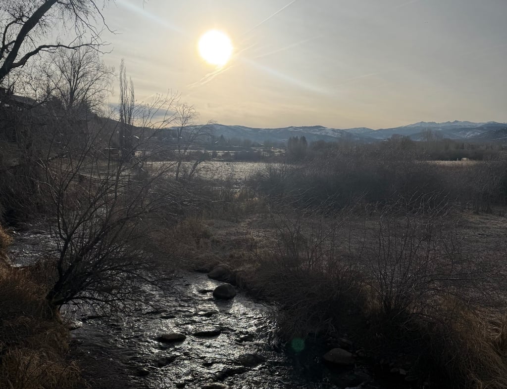 a river with a sun setting on the horizon