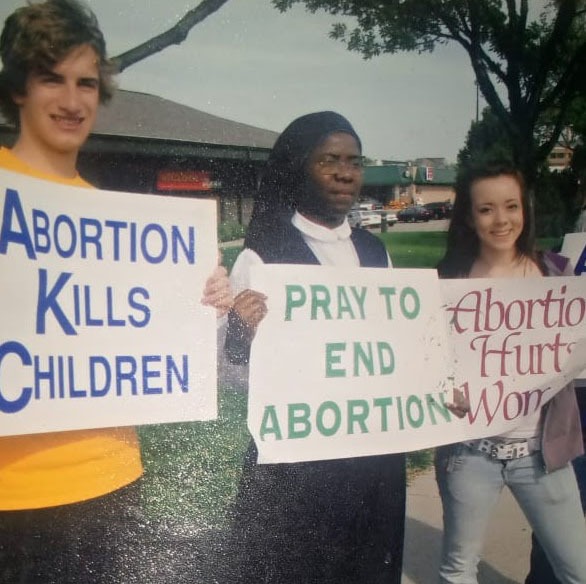 A group of pro-life protesters including a nun holding anti-abortion signs at a public demonstration.