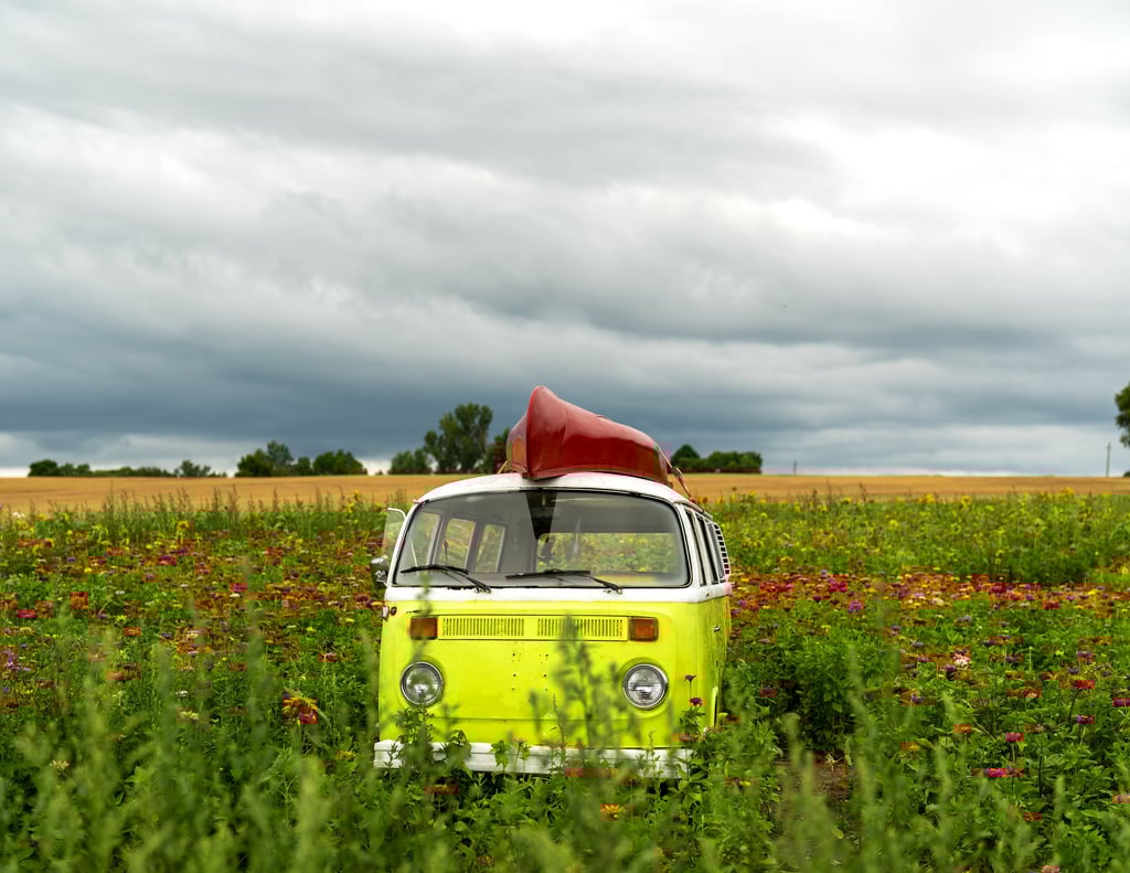 a yellow van parked in a field with a canoe on it