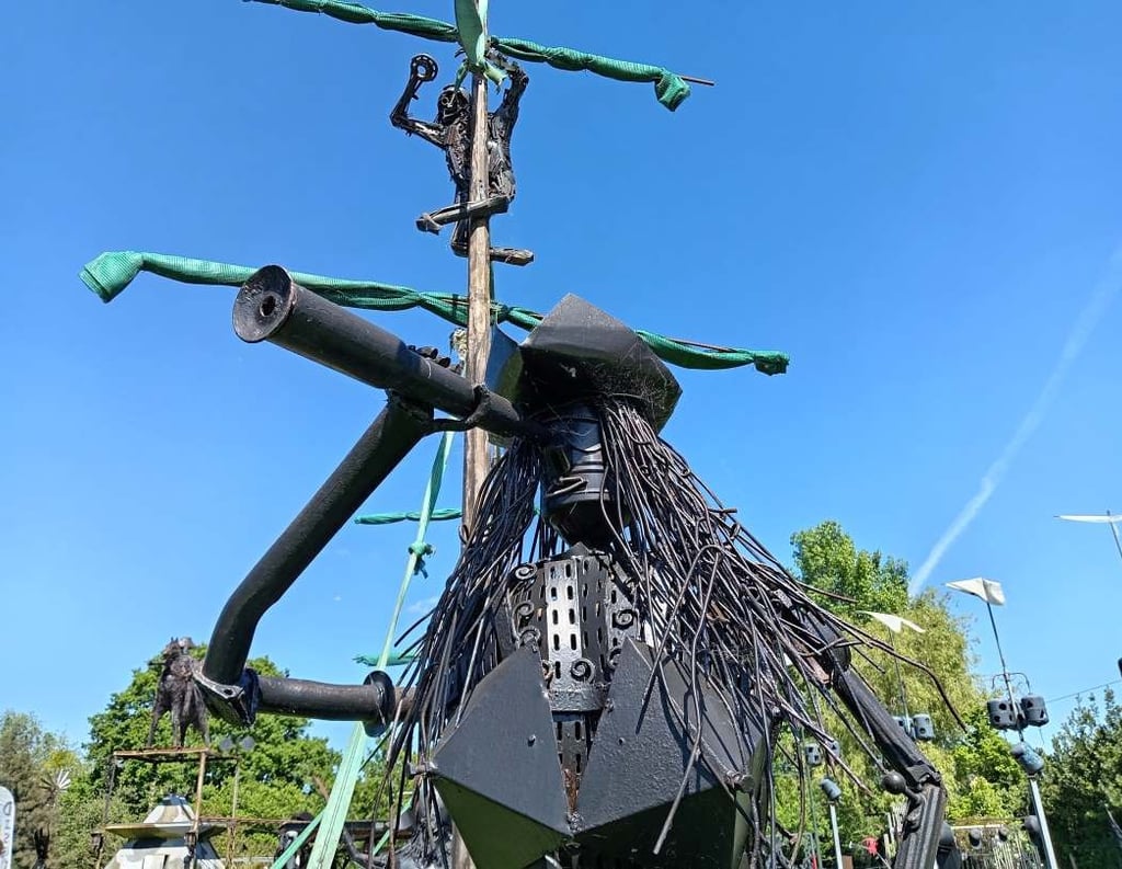 Creative pirate ship sculpture made of recycled metal scrap art under a clear blue sky.