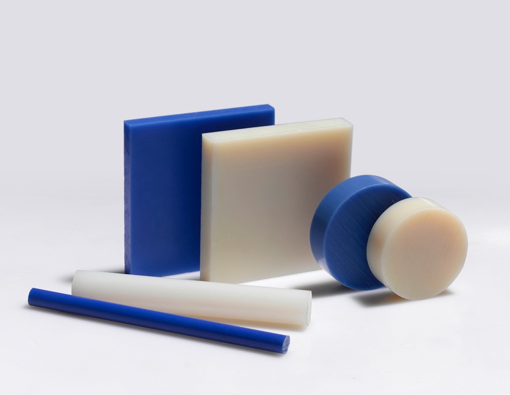 Assorted blue and white industrial plastic sheets, rods, and discs for engineering fabrication.